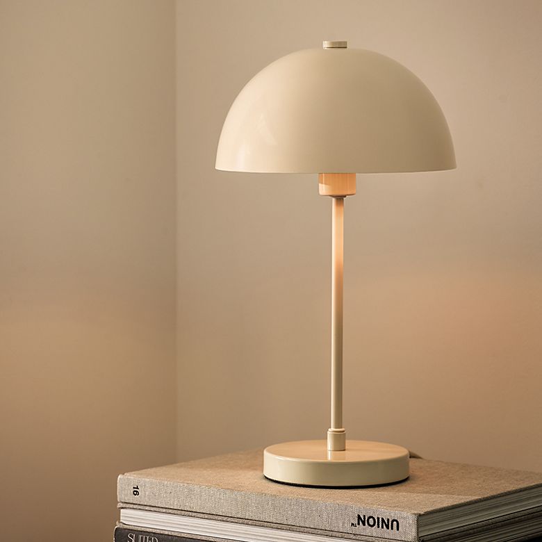 Cream domed table lamp on a bedside table. Shop table lamps