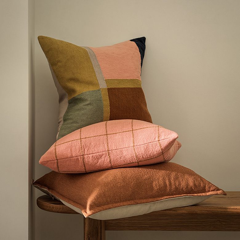 Assorted cushions in various colours stacked up. Shop cushions  
