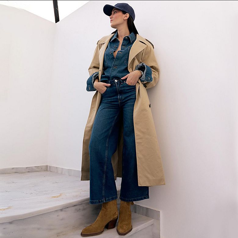 Instagram content creator Malamatenia Palatsidi wearing a beige trench coat, denim shirt, wide-leg jeans and brown suede boots. Shop women’s new-in