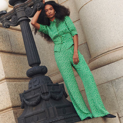 Woman wearing green patterned blouse and trousers co-ord for a city hen do. Shop co-ords 