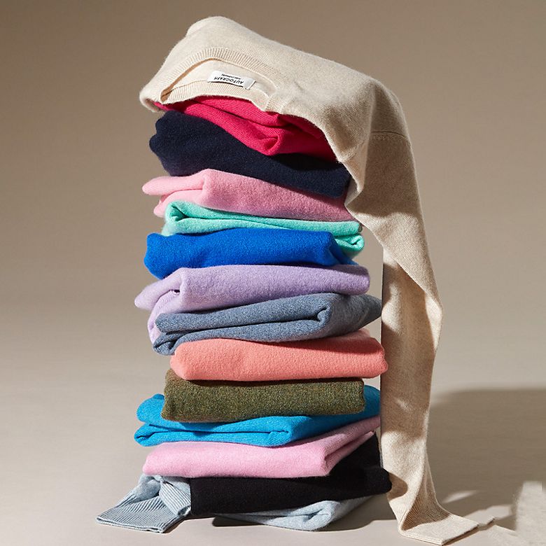 Stack of folded cashmere jumpers. Shop women’s cashmere